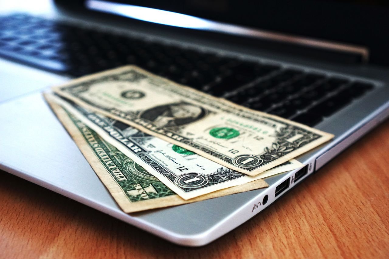 about-02 Close-up of US dollar bills placed on a laptop symbolizing digital finance and economy.