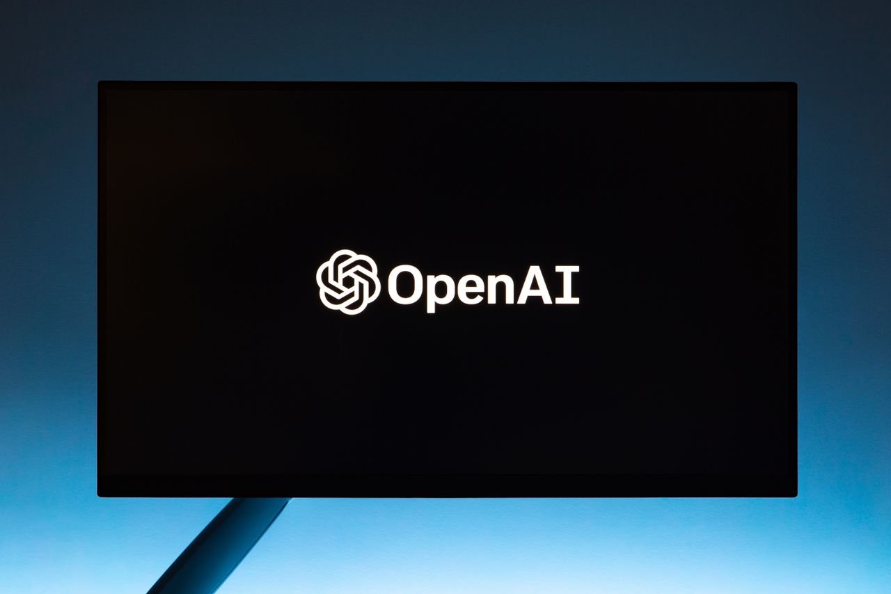 hero-02 Minimalist display of OpenAI logo on a screen, set against a gradient blue background.